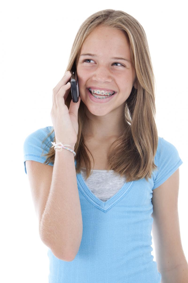 Mädchen mit Zahnspange ruft bei Dr. Köneke zur Terminvereinbarung an und lächelt